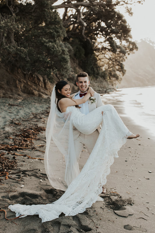 Groom holding a bride wearing a strapless lace bridal gown with long veil